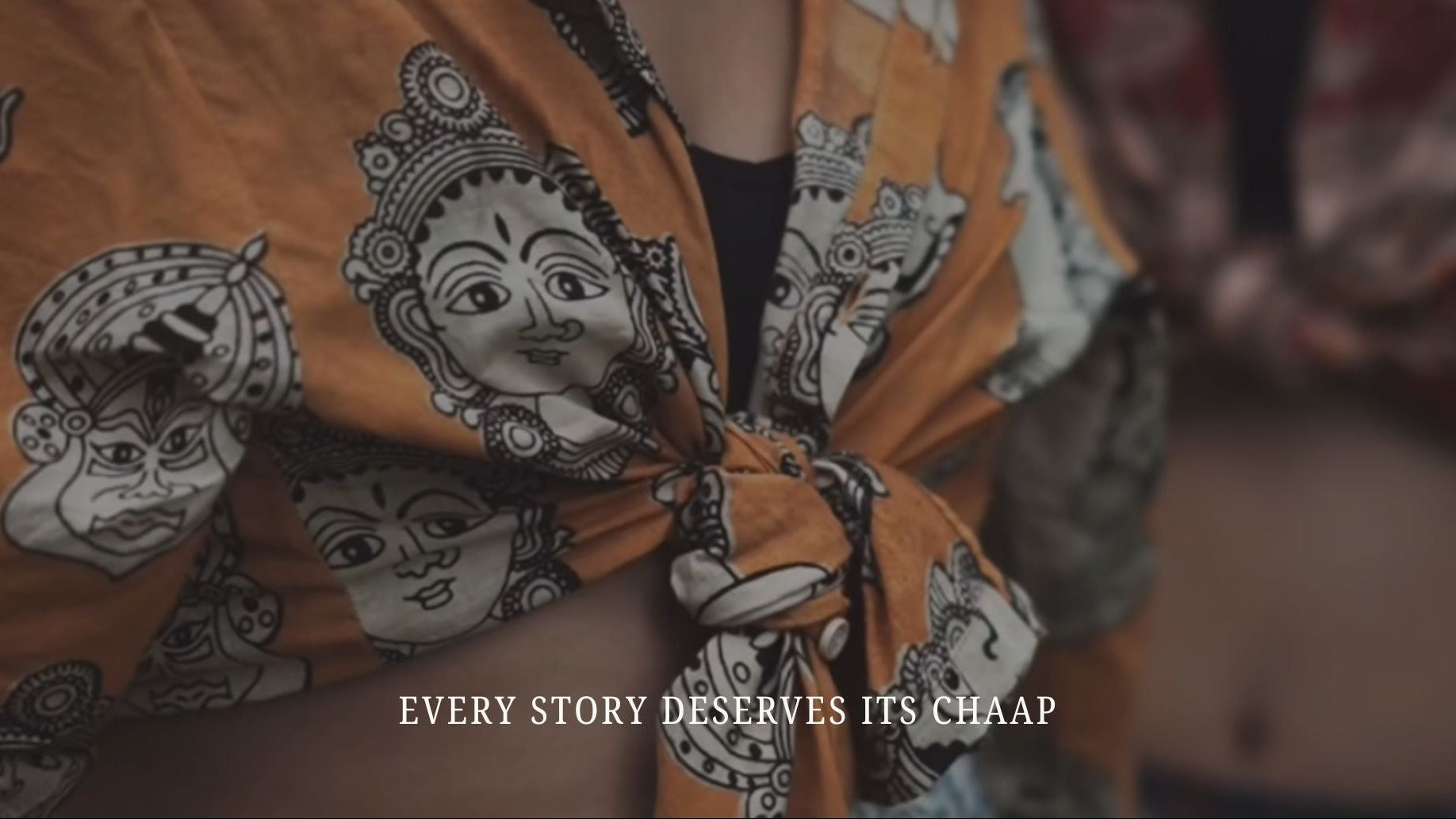 Person wearing an orange garment with face patterns and text 'EVERY STORY DESERVES ITS CHAAP'.